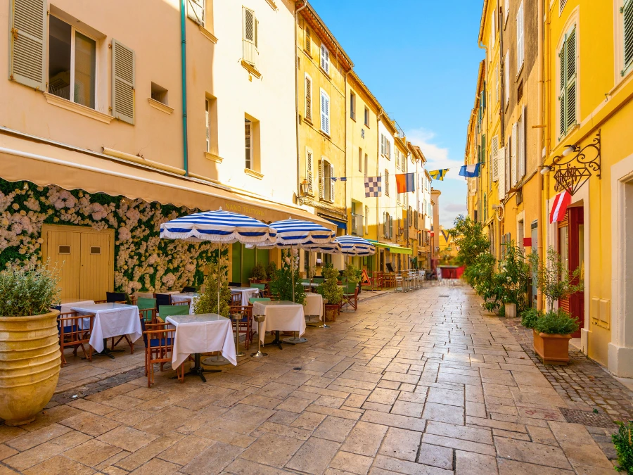 A picturesque alley of shops and sidewalk cafes in the colorful old town section of the Mediterranean resort city of Saint-Tropez, France, along the French Riviera